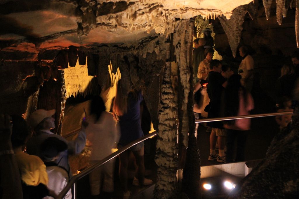 In this picture I can see few people standing and I can see lights and It looks like a cave.